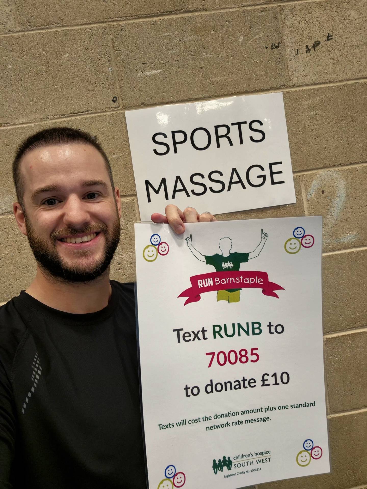 Ryan holding a sports massage sign and a RUN Barnstaple charity poster